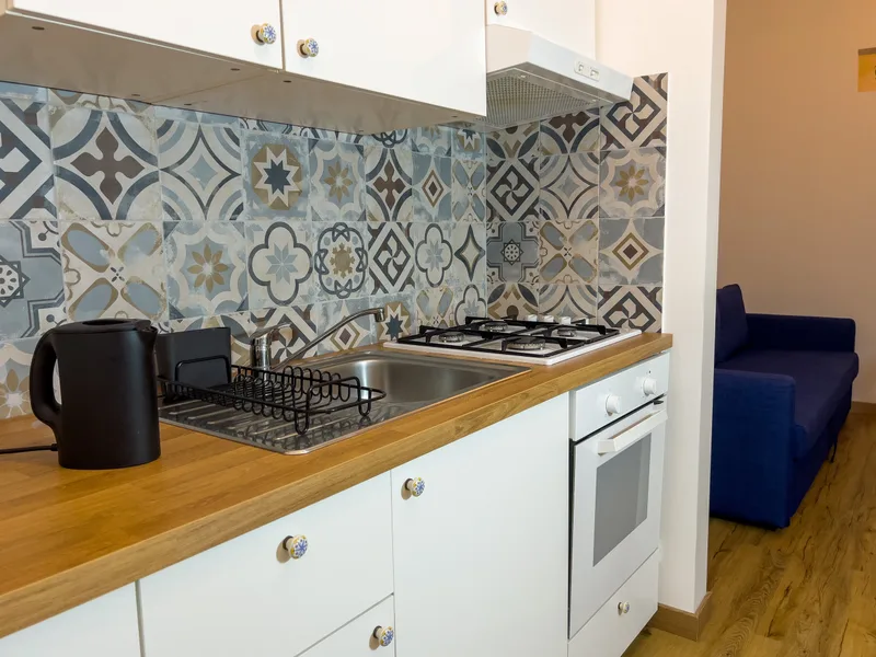 Cucina attrezzata con lavello, piano cottura a gas, forno, bollitore e piastrelle patchwork